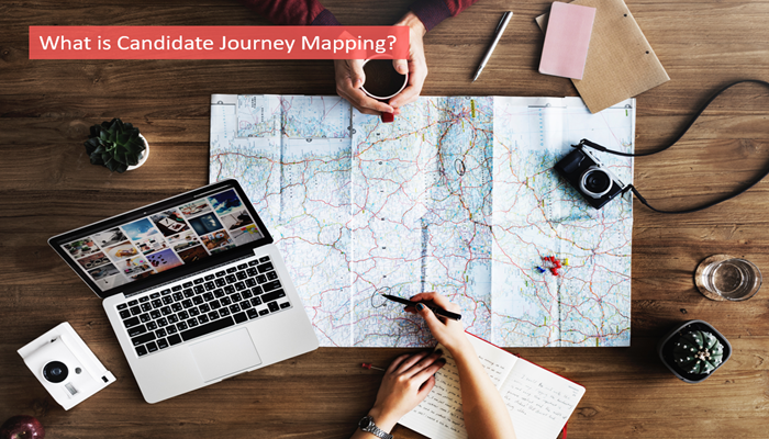 Overhead view of a map with laptop, camera, and hands planning a journey.